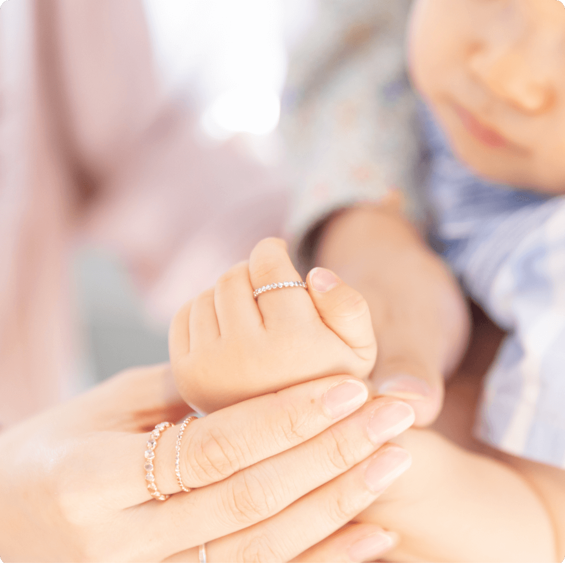 ベビーリングを着けた赤ちゃんの手に添える母の指にも指輪